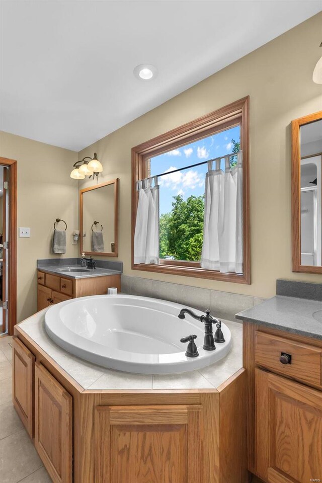 bathroom with tiled tub, dual vanity, and tile patterned floors