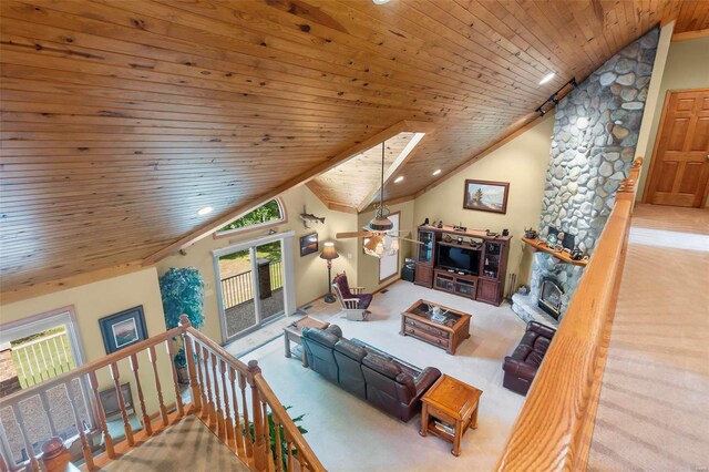 carpeted dining space with a skylight, a stone fireplace, high vaulted ceiling, and wooden ceiling