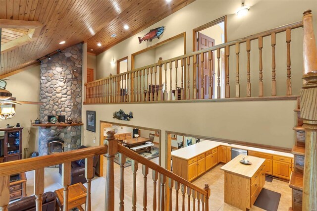 stairway featuring lofted ceiling, light tile patterned floors, wood ceiling, ceiling fan, and a stone fireplace