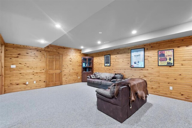 carpeted living room featuring wood walls