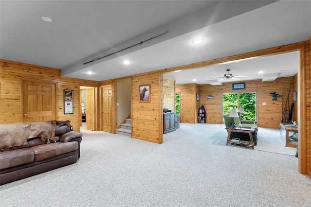 carpeted living area featuring beam ceiling, recessed lighting, stairway, a ceiling fan, and wooden walls