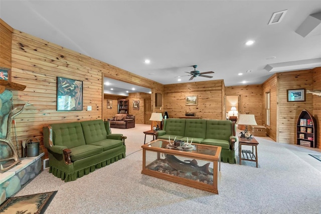 carpeted living area with wooden walls, a ceiling fan, visible vents, and recessed lighting