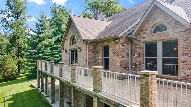 view of front of home with a shingled roof, a chimney, a front lawn, and brick siding