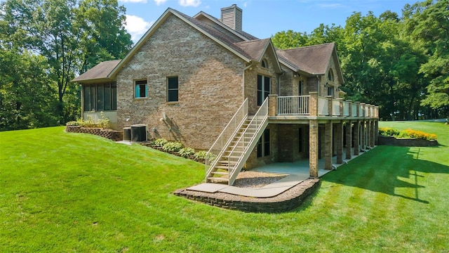 rear view of house featuring brick siding, a yard, and stairs