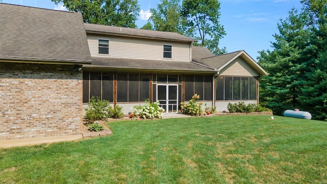 rear view of house featuring a yard, brick siding, and a sunroom