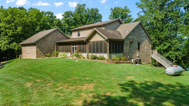 view of front facade with central air condition unit, a sunroom, and a front yard