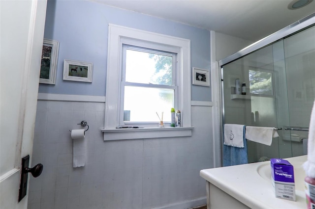 bathroom featuring walk in shower, vanity, and tile walls