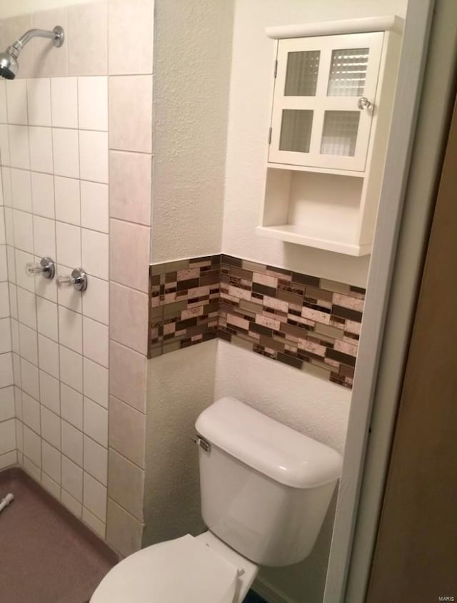 bathroom featuring toilet and tiled shower