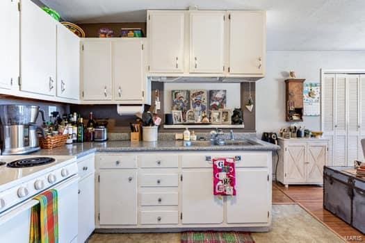 kitchen featuring white cabinetry, sink, and light wood-type flooring