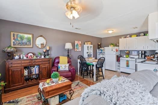 living room with ceiling fan and light hardwood / wood-style flooring