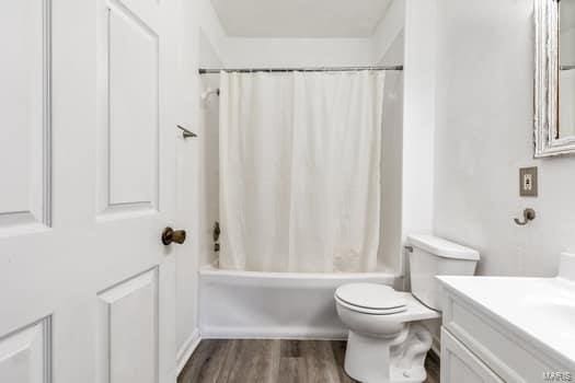 full bathroom featuring vanity, wood-type flooring, toilet, and shower / bathtub combination with curtain