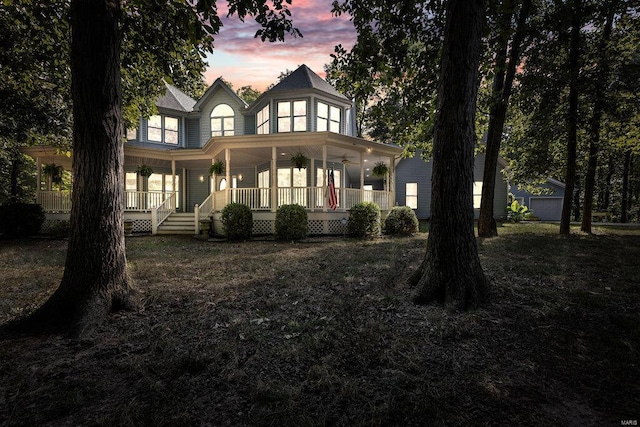 back house at dusk featuring a garage and covered porch