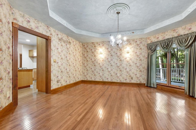 spare room with wood-type flooring and a tray ceiling