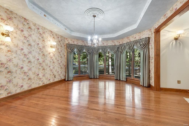 unfurnished room featuring wood-type flooring, a raised ceiling, and plenty of natural light