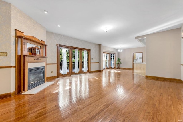 unfurnished living room featuring light hardwood / wood-style floors and an inviting chandelier