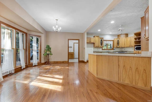 kitchen featuring light brown cabinets, ceiling fan with notable chandelier, light hardwood / wood-style flooring, and kitchen peninsula