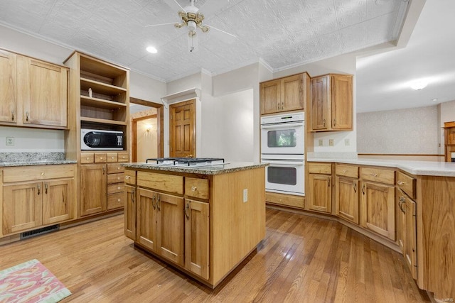 kitchen featuring ceiling fan, white appliances, crown molding, a center island, and light wood-type flooring