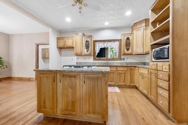 kitchen with light hardwood / wood-style floors, light stone countertops, light brown cabinetry, and white microwave