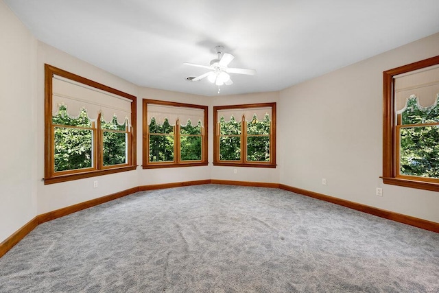 carpeted empty room with a wealth of natural light and ceiling fan