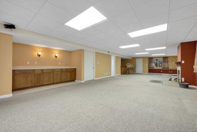 basement with a paneled ceiling and light carpet