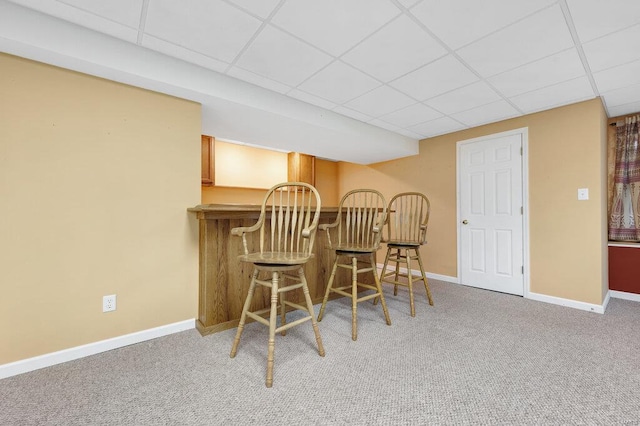 dining area with a drop ceiling, indoor bar, and carpet