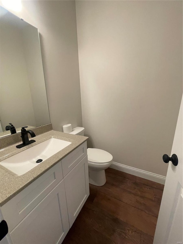 bathroom featuring toilet, vanity, and wood-type flooring