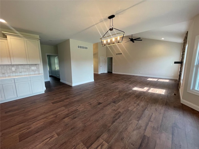 interior space featuring ceiling fan with notable chandelier and dark hardwood / wood-style flooring