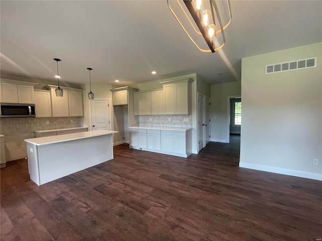 kitchen featuring dark hardwood / wood-style flooring, hanging light fixtures, a center island, and backsplash