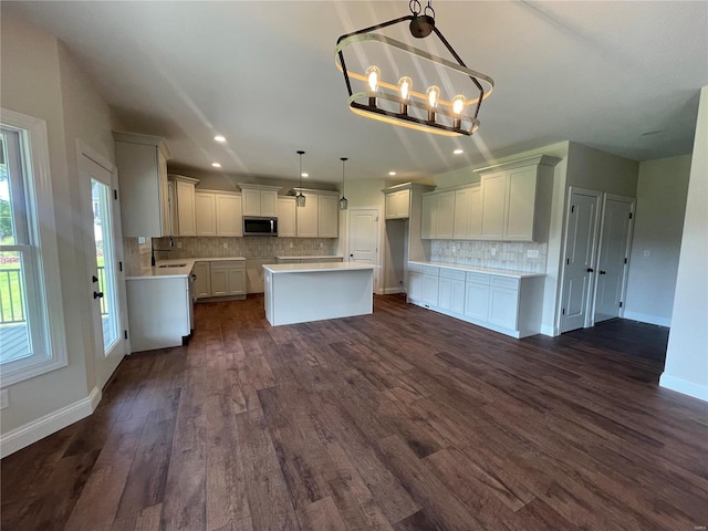 kitchen featuring a center island, dark wood-type flooring, a chandelier, pendant lighting, and white cabinets