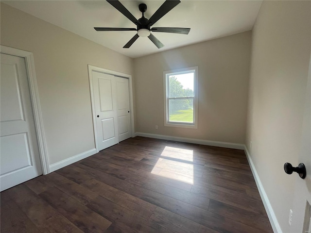 unfurnished bedroom with ceiling fan and dark wood-type flooring