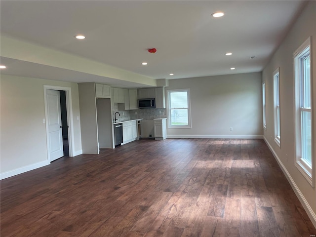 unfurnished living room featuring a wealth of natural light, hardwood / wood-style flooring, and sink