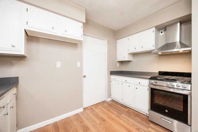 kitchen featuring white cabinets, stainless steel range with gas cooktop, and wall chimney exhaust hood