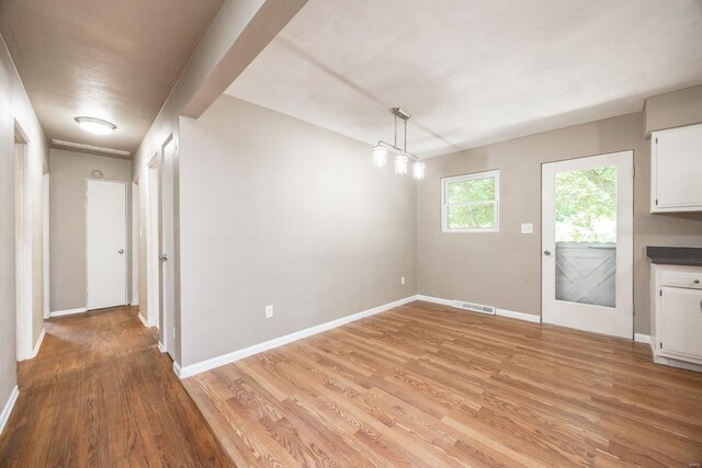 unfurnished dining area featuring an inviting chandelier and light hardwood / wood-style flooring