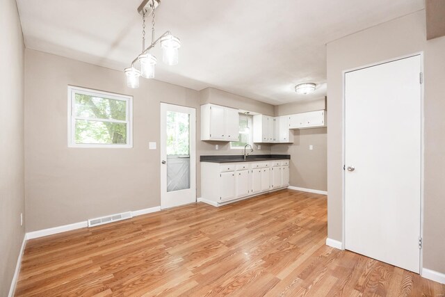 kitchen with white cabinets, decorative light fixtures, sink, and light hardwood / wood-style flooring