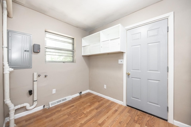 washroom with electric panel, hookup for a washing machine, and light hardwood / wood-style floors