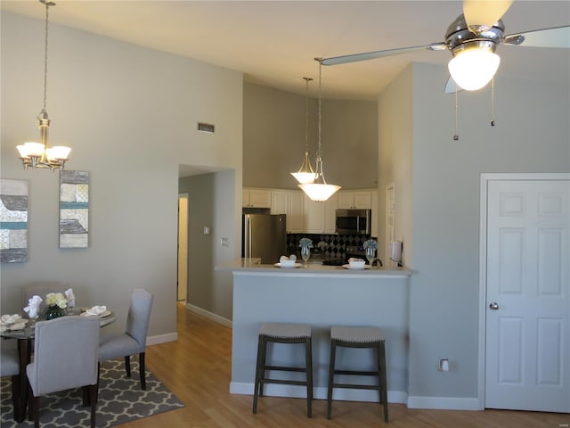 kitchen with visible vents, hanging light fixtures, appliances with stainless steel finishes, white cabinets, and a peninsula