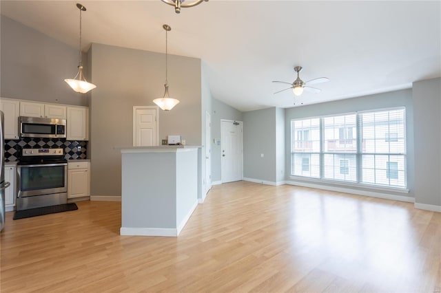 kitchen with light wood finished floors, tasteful backsplash, appliances with stainless steel finishes, and a ceiling fan