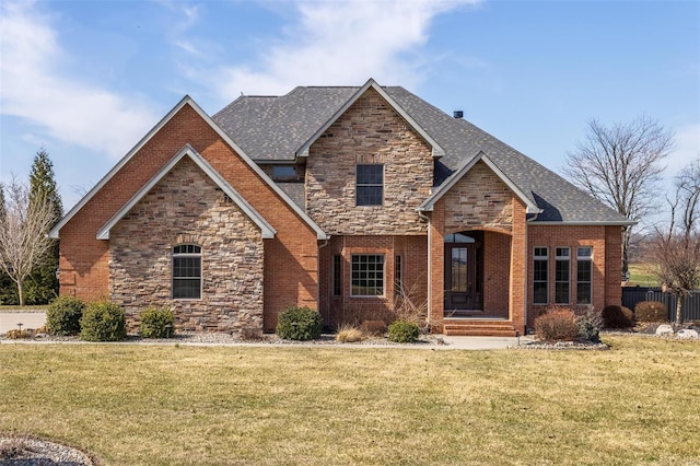 view of front of house featuring brick siding, stone siding, a front lawn, and fence