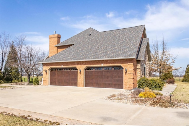 view of side of property featuring concrete driveway, a chimney, brick siding, and a shingled roof