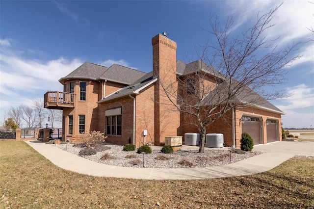 back of house featuring brick siding, cooling unit, a garage, a balcony, and a chimney