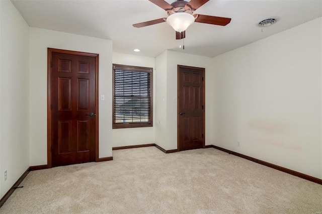 unfurnished room with visible vents, light carpet, baseboards, and a ceiling fan