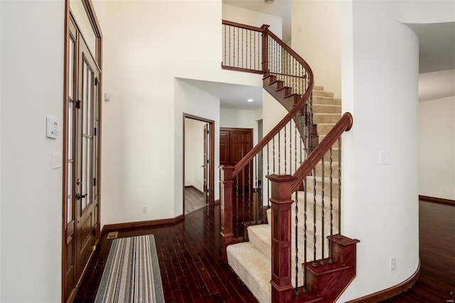 entrance foyer with stairway, a high ceiling, baseboards, and wood-type flooring