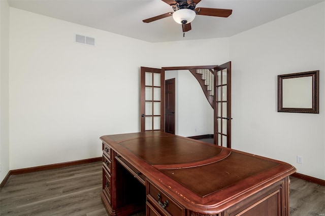 unfurnished office with visible vents, a ceiling fan, dark wood-style flooring, and baseboards