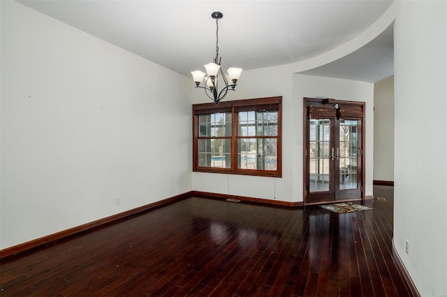 unfurnished room featuring hardwood / wood-style floors, an inviting chandelier, french doors, and baseboards