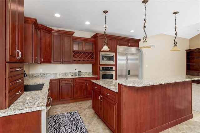 kitchen with a sink, a center island, recessed lighting, built in appliances, and hanging light fixtures