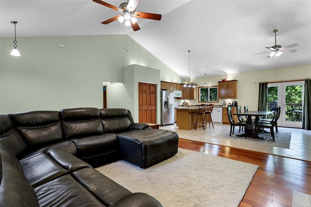 living room with high vaulted ceiling, wood-type flooring, ceiling fan, and french doors