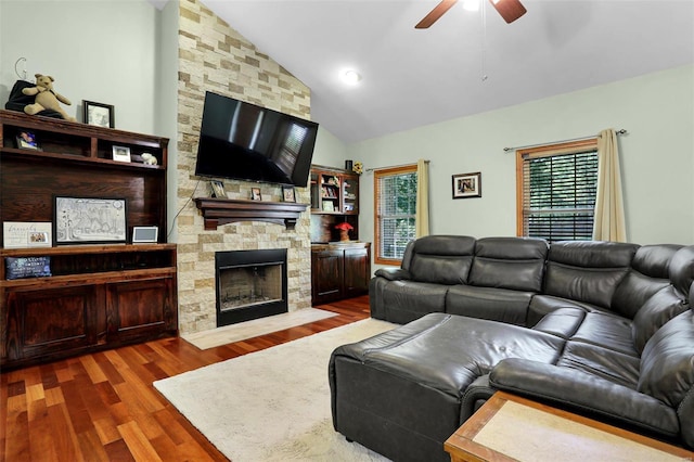 living room featuring ceiling fan, a stone fireplace, hardwood / wood-style floors, and high vaulted ceiling