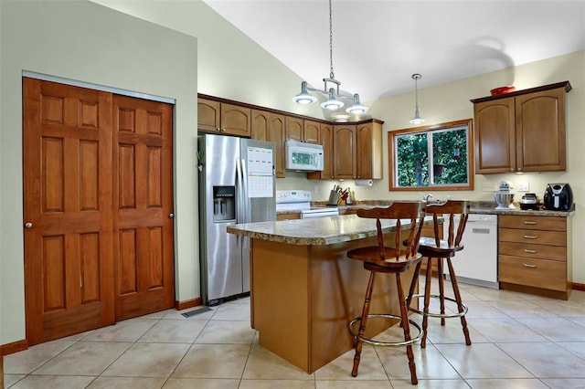 kitchen featuring a center island, light tile patterned flooring, vaulted ceiling, hanging light fixtures, and white appliances