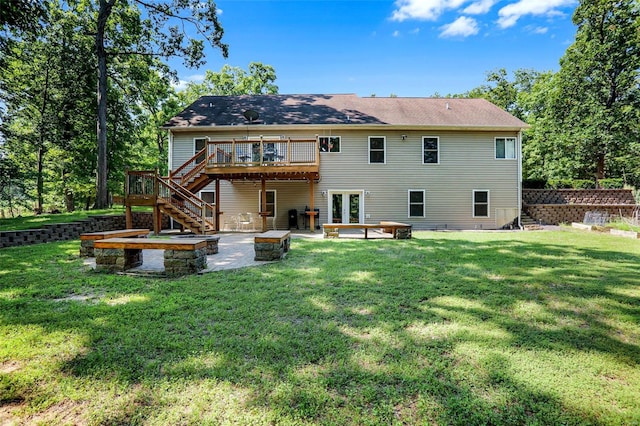 back of property with a yard, an outdoor fire pit, a wooden deck, and a patio area