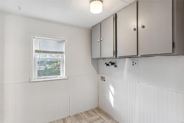 laundry room featuring washer hookup, wainscoting, cabinet space, and light wood finished floors